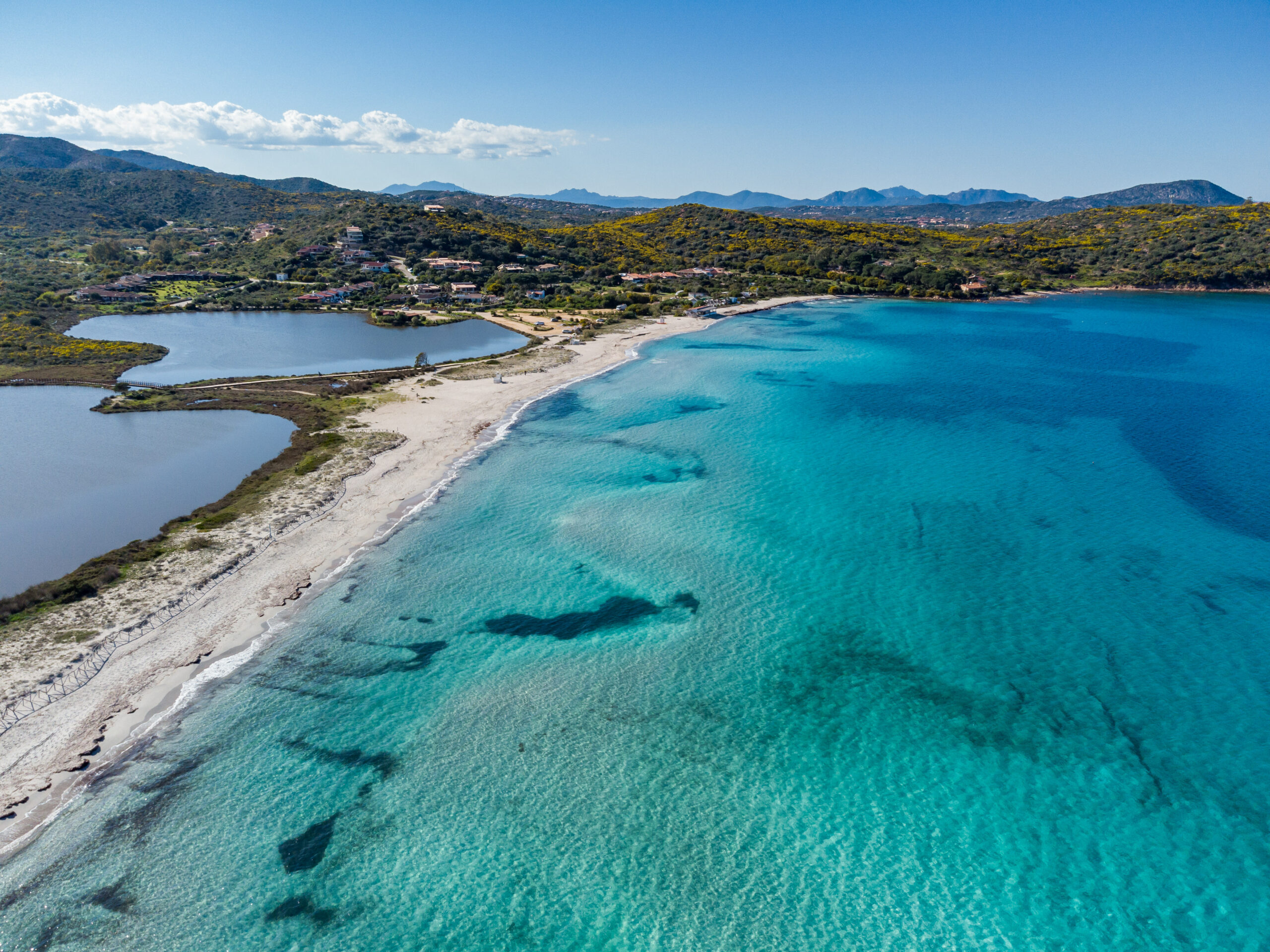 Panoramablick auf den Strand Porto Taverna in Nord-Sardinien mit türkisblauem Meer, feinem Sandstrand und Blick auf die Insel Tavolara im Hintergrund.